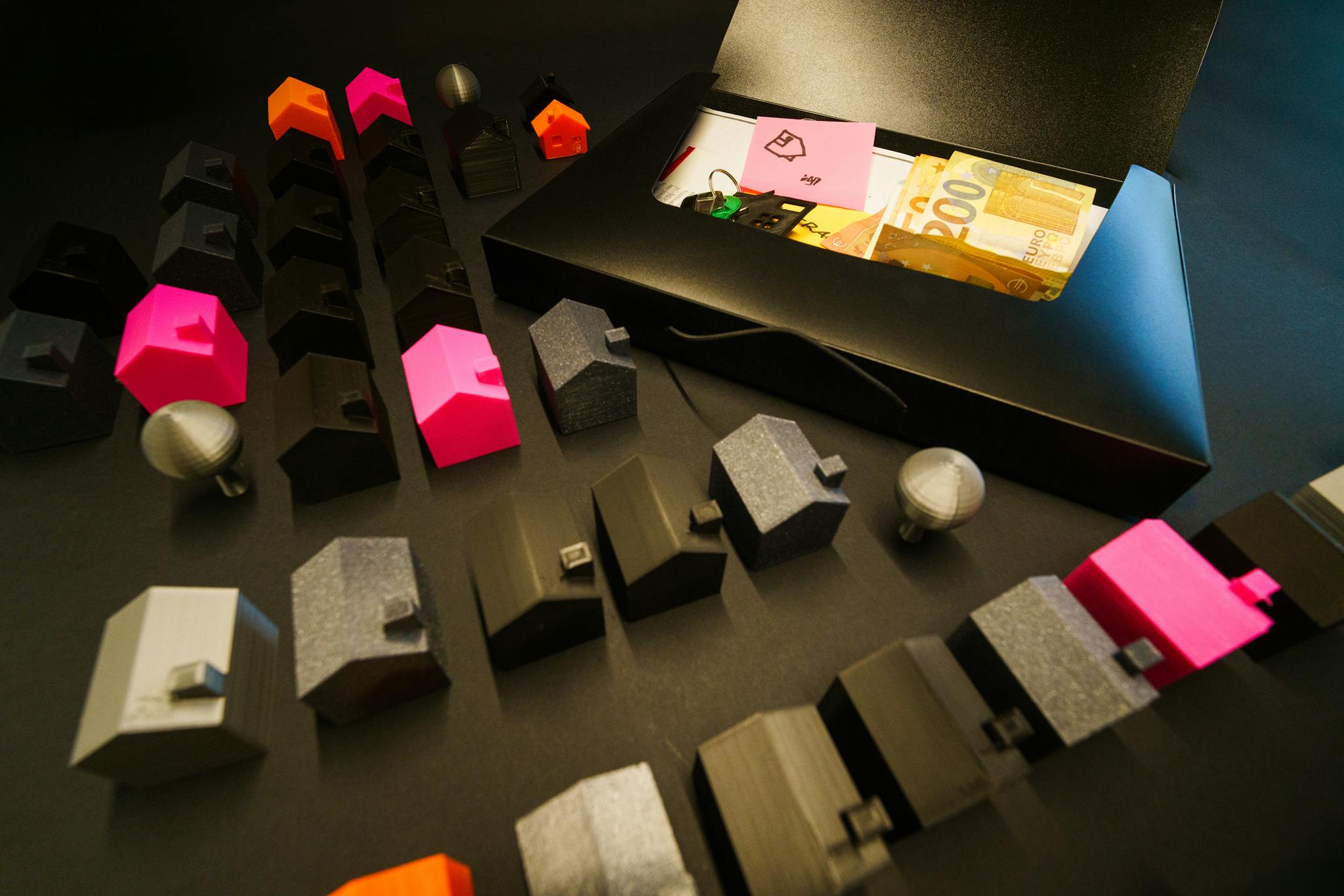 Colorful miniature houses and Euro banknotes in a case representing real estate and finance.